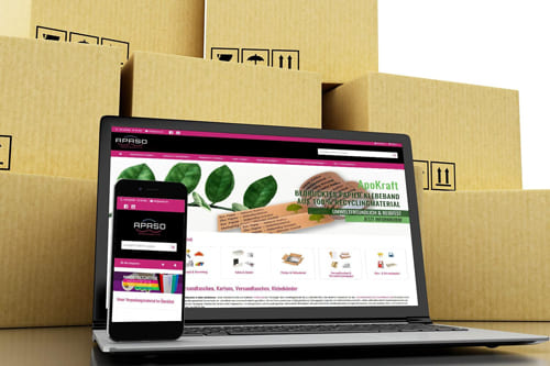 Onlineshop Referenz von APASO Verpackungen e.K. für Verpackungsmaterialien auf Laptop und Smartphone vor Kartons Laptop und Smartphone mit einem Onlineshop über Verpackungsmaterialien von APASO Verpackungen e.K., umgeben von Kartons